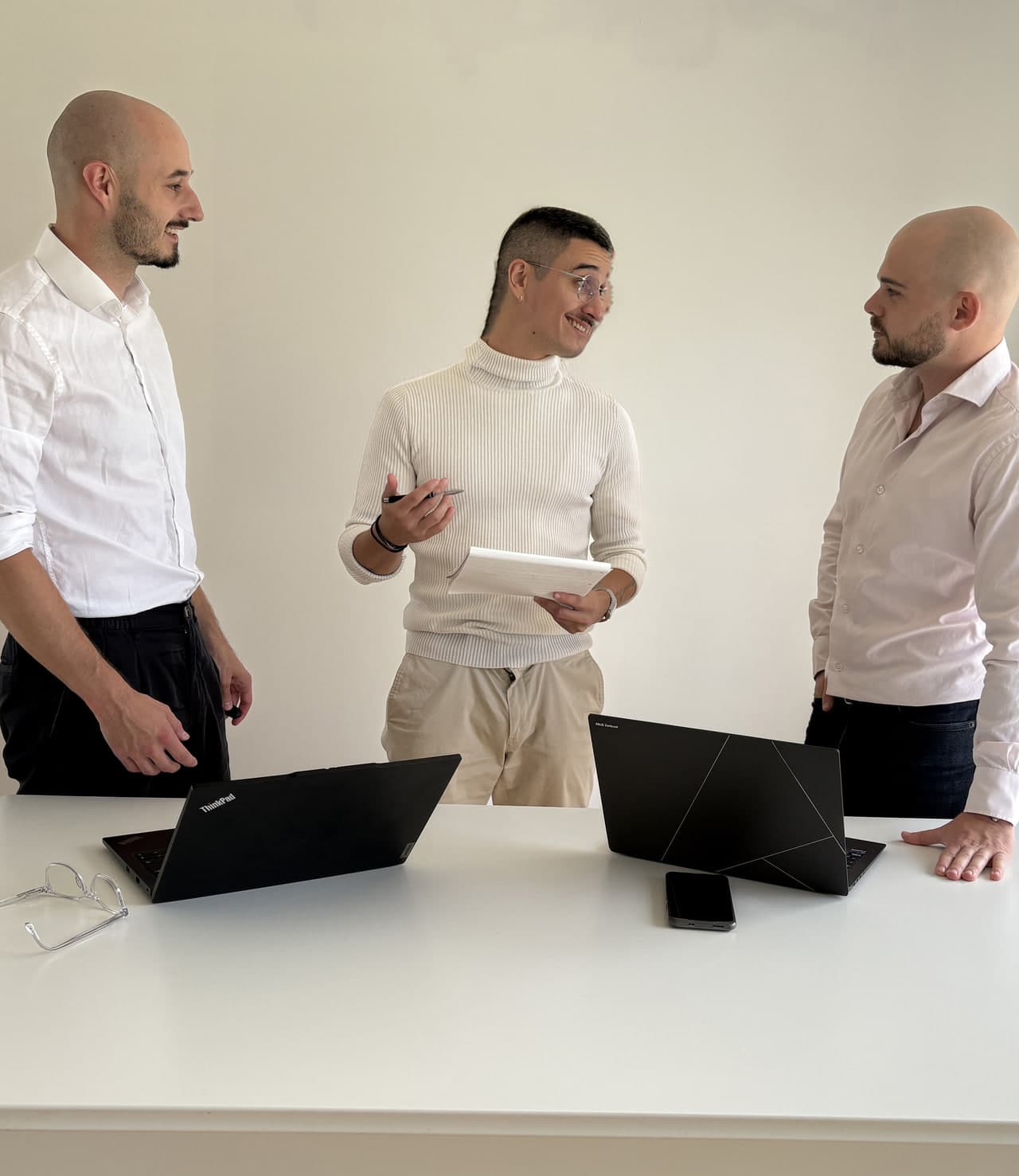 Les trois consultants de Lumeni en échange debout autour d’une table de travail